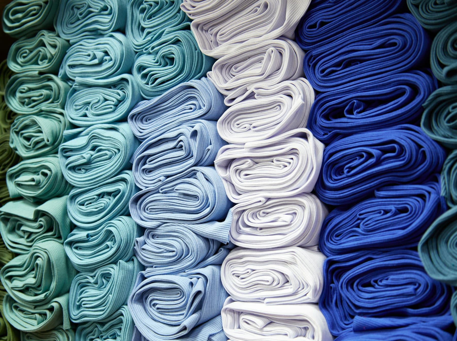 Folded knitted fabric stacked by shade, greens through blues