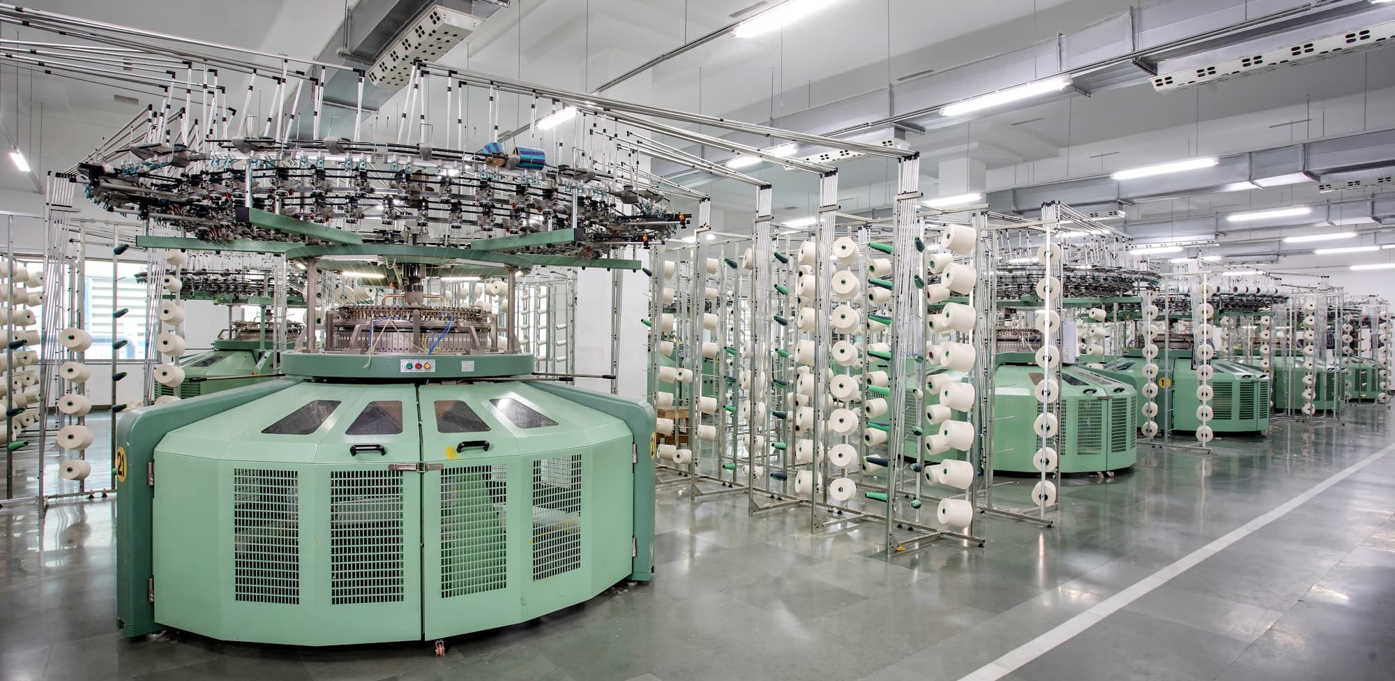 Circular knitting machines and yarn creels on a knitting factory floor
