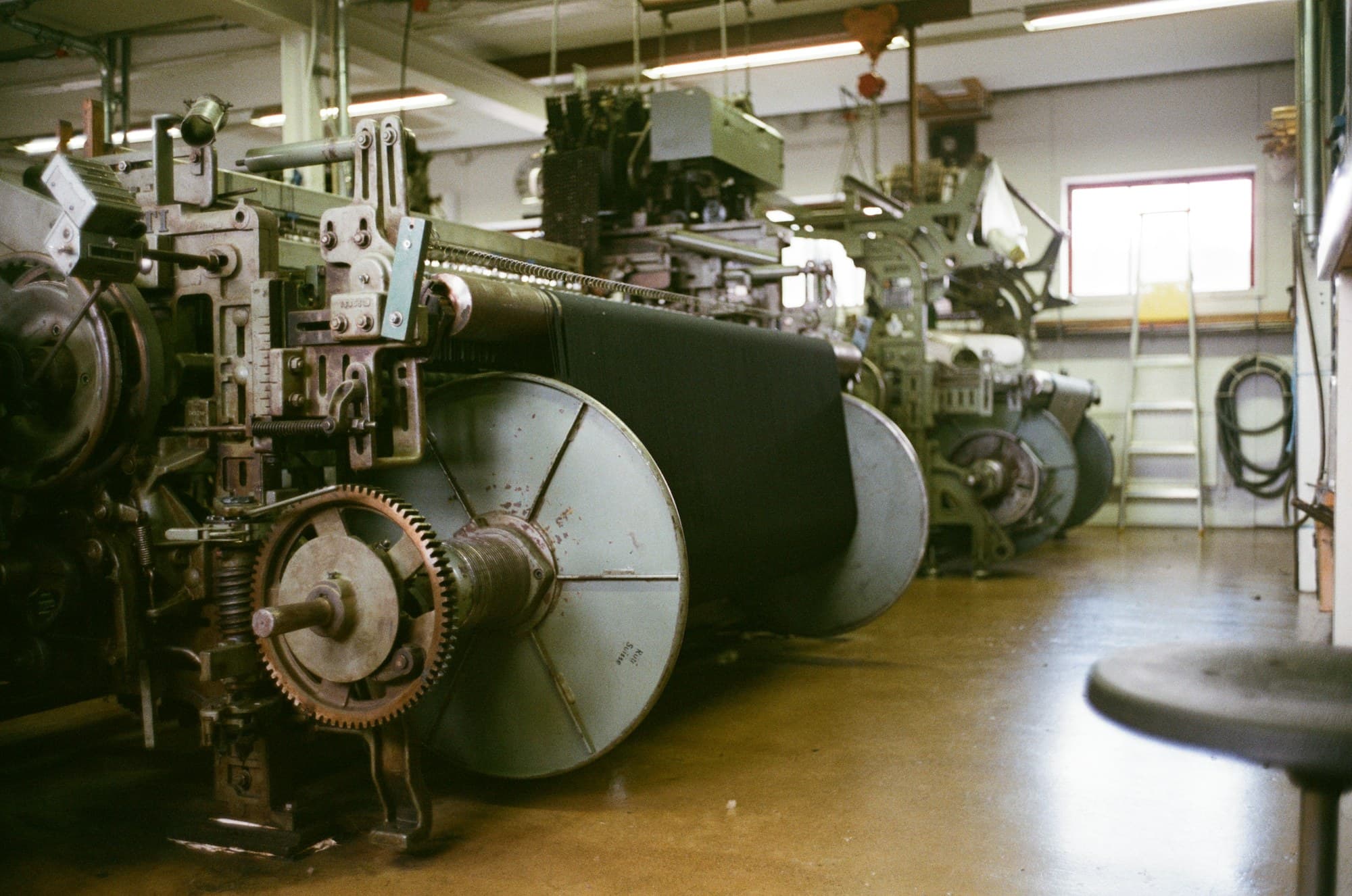 A row of looms with woven cloth on the beams