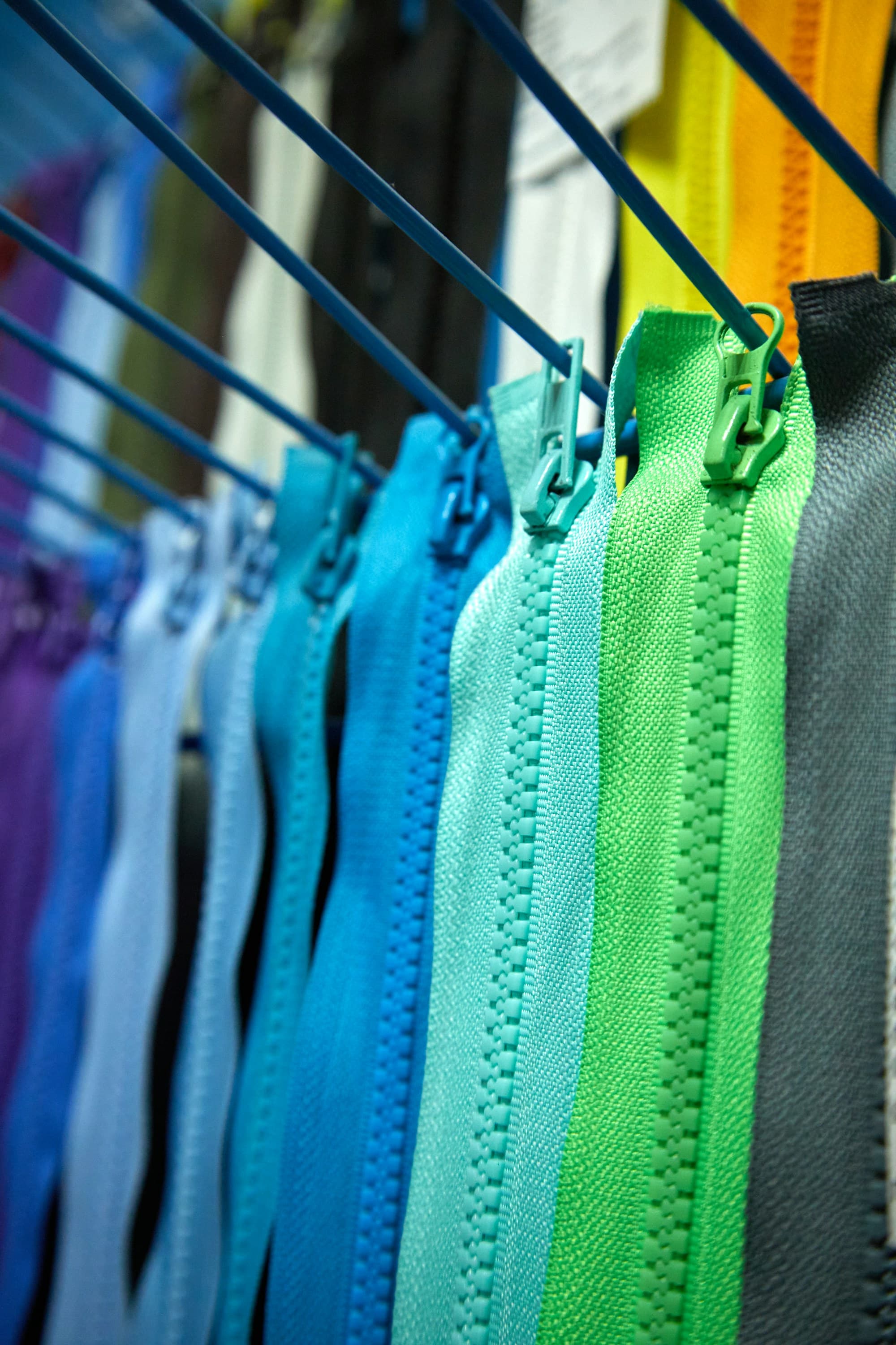 A shade range of zippers hung in a row