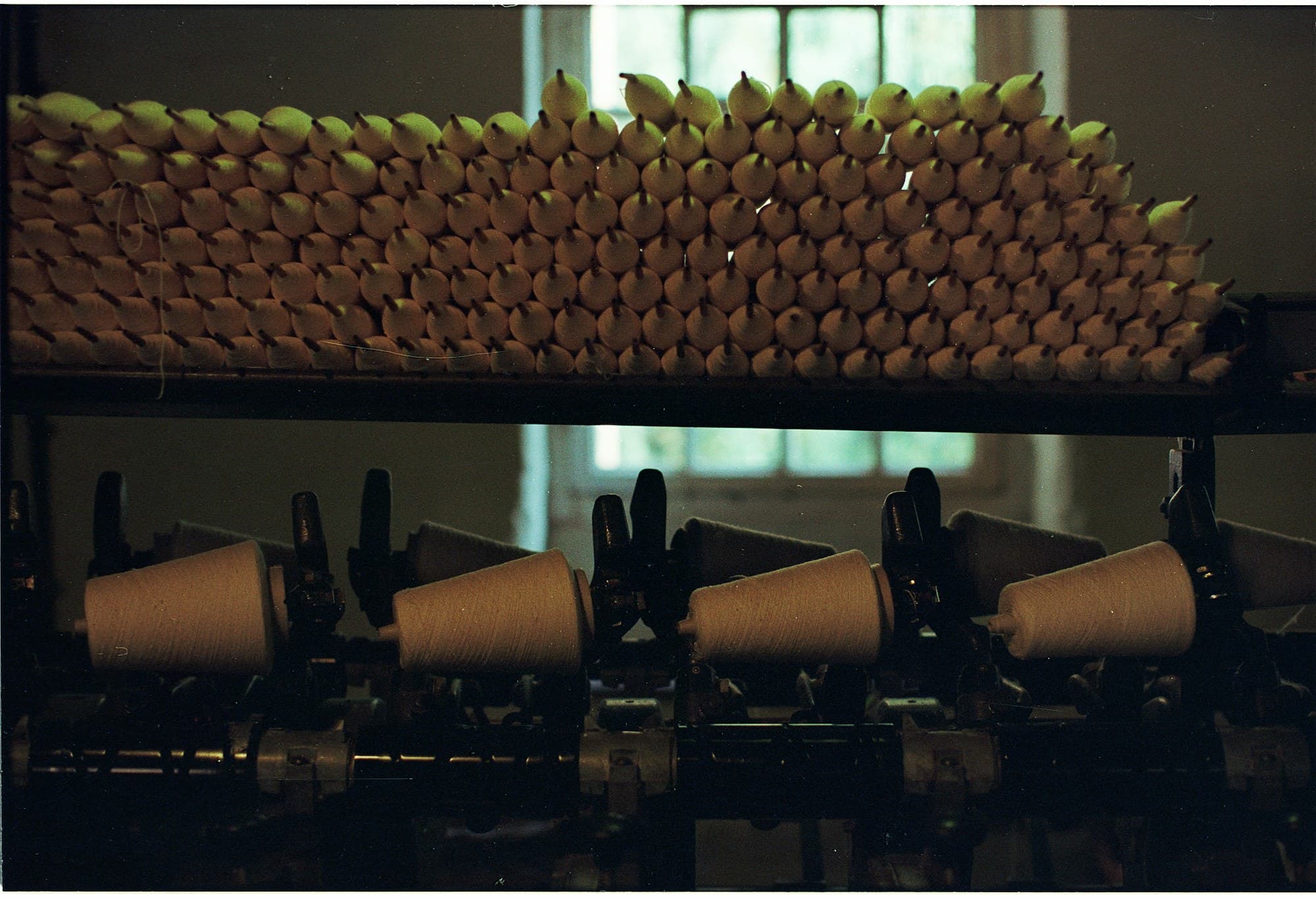 Racks of wound yarn cones above a winding machine